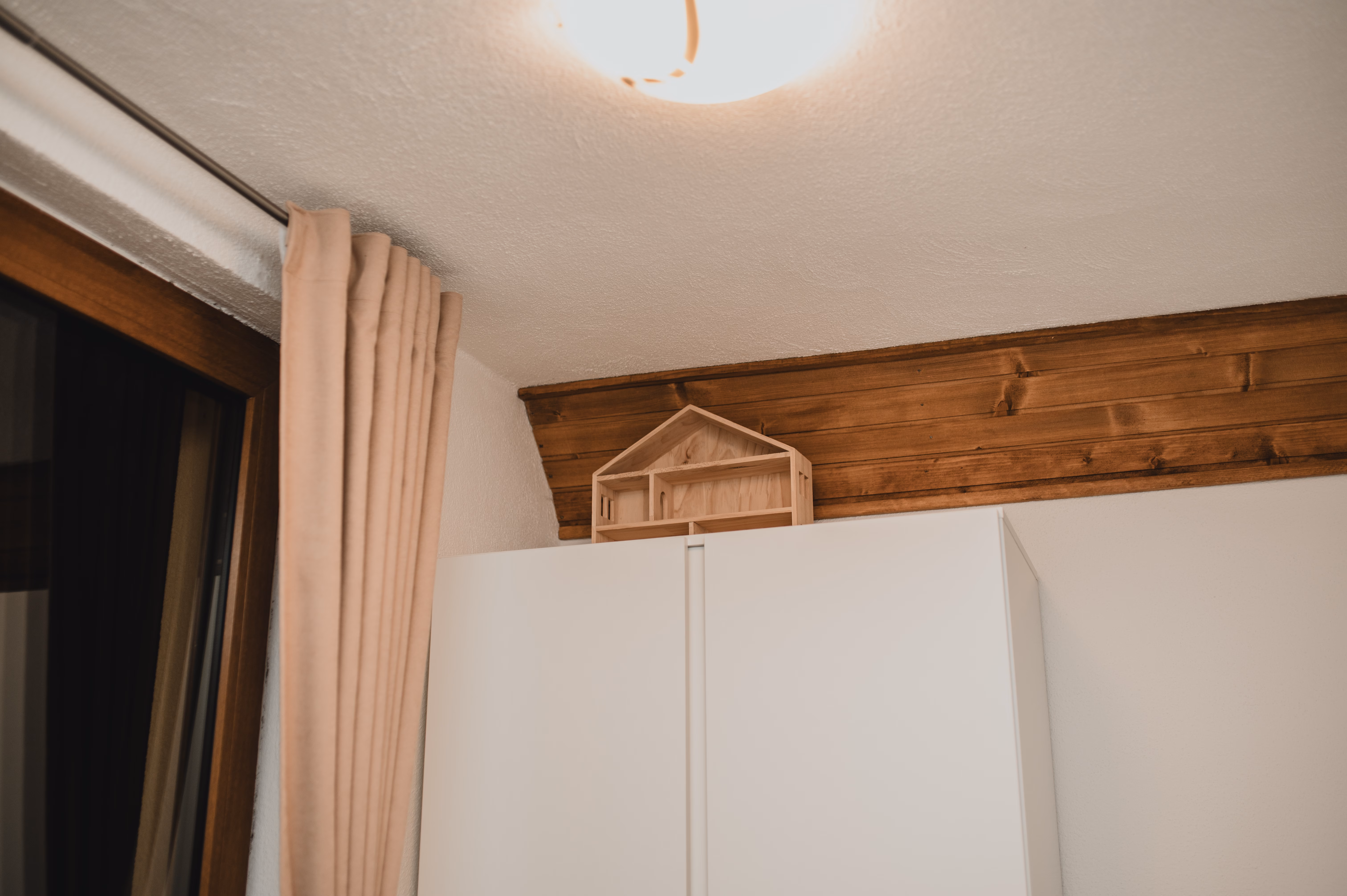 Šarmantni detalji sobe s drvenom gredom na stropu i policom u obliku kuće