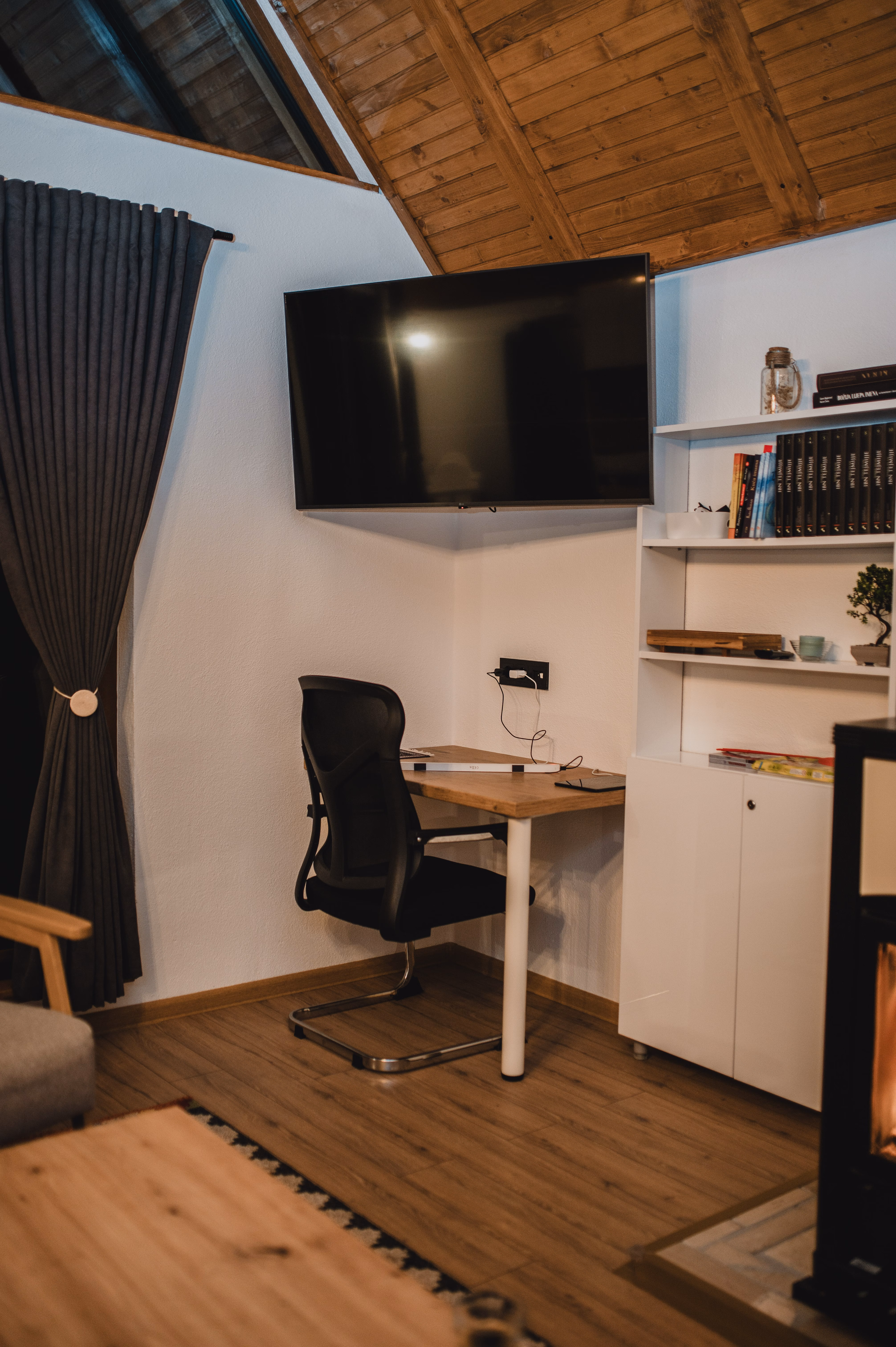 Radni kutak s pisaćim stolom, TV-om i visokim drvenim stropom